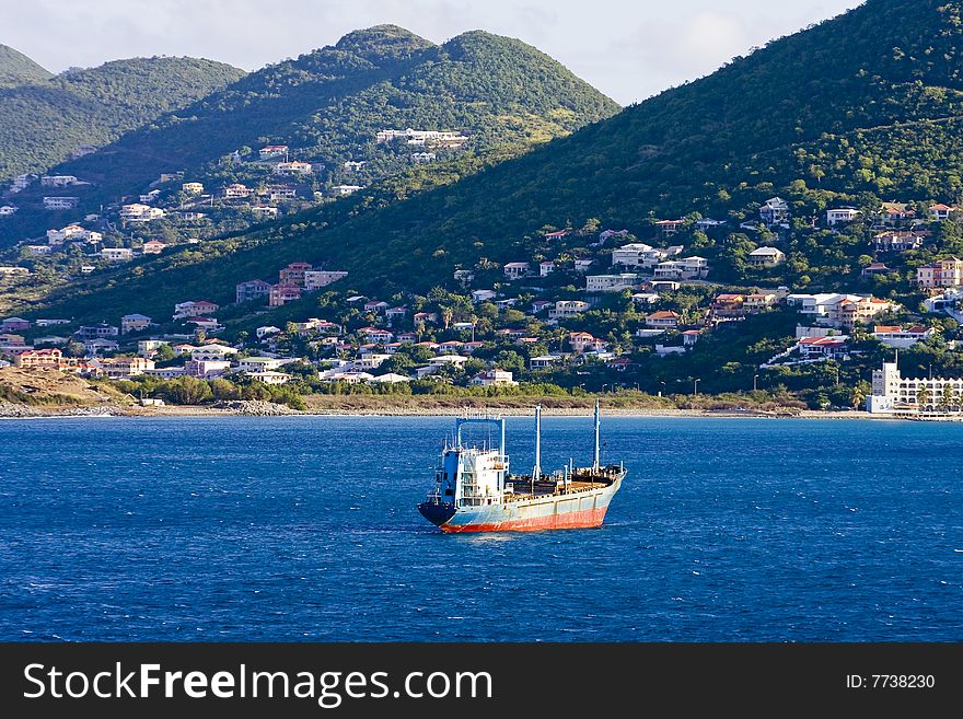 The coast off a tropical island with a tanker ship sailing in. The coast off a tropical island with a tanker ship sailing in