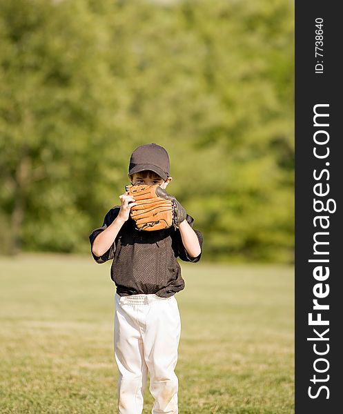 Little Boy Hiding Behind His Glove During a Baseball Game