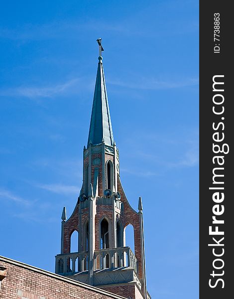 An old church steeple with bell tower against a blue sky. An old church steeple with bell tower against a blue sky