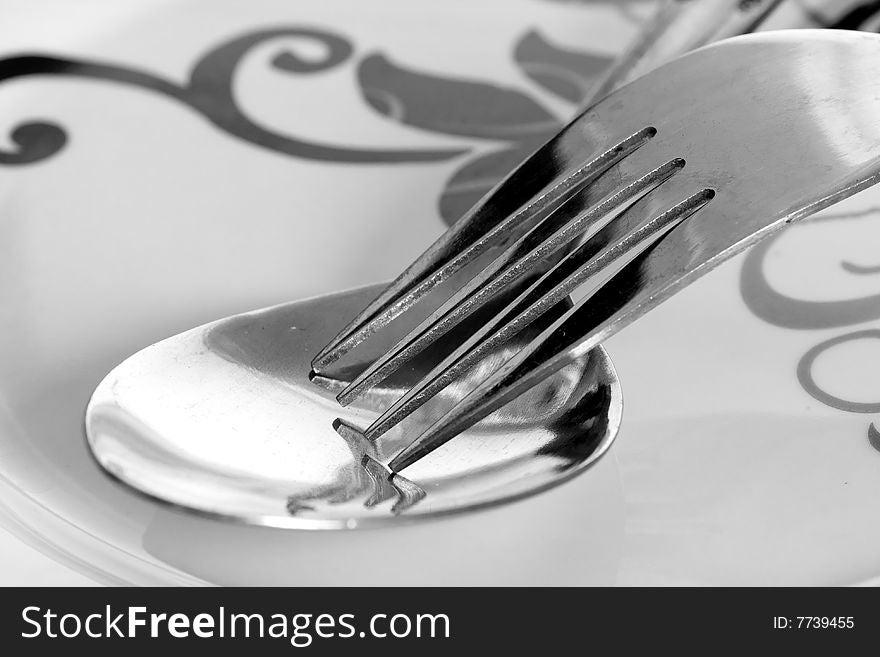 Detail of fork and spoon on white plate. Detail of fork and spoon on white plate