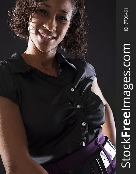 Young adult black woman with smile while leaning forward, backlit on black background. Young adult black woman with smile while leaning forward, backlit on black background.