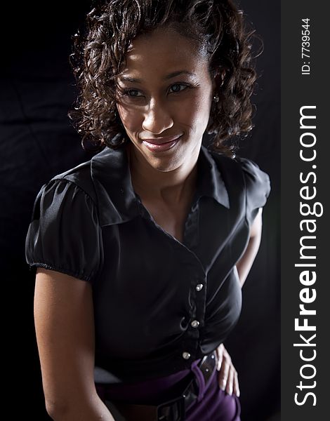 Young adult black woman with smile while leaning forward, backlit on black background. Young adult black woman with smile while leaning forward, backlit on black background.