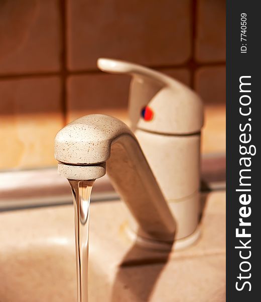 Closeup of water flowing into sink from a faucet in the kitchen. Closeup of water flowing into sink from a faucet in the kitchen.