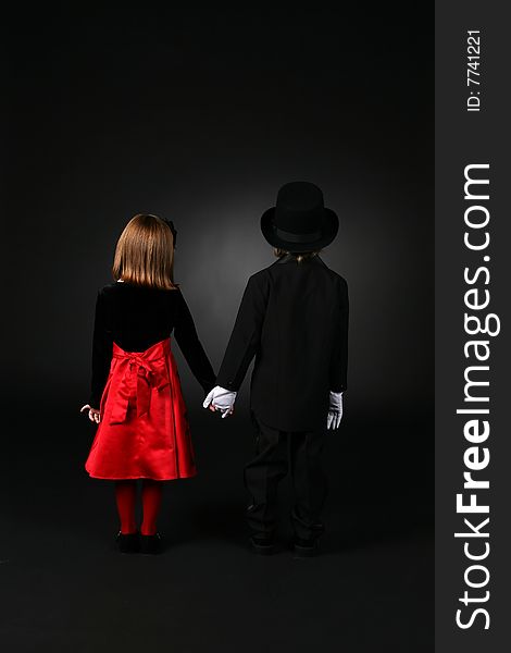 Boy and girl in formal clothing standing back to and holding hands. Boy and girl in formal clothing standing back to and holding hands