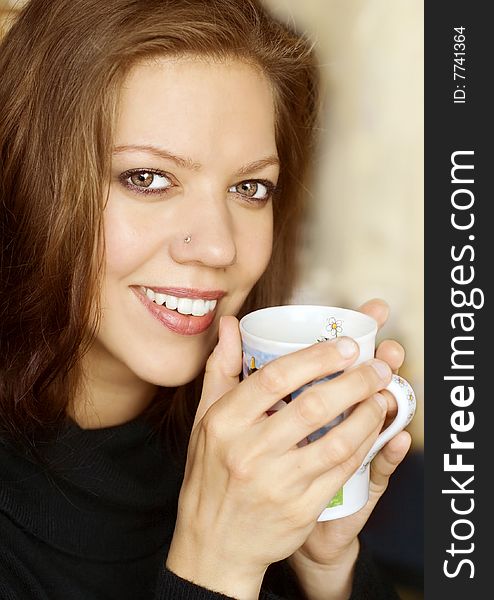 Young woman holding cup of coffee and is smiling happy. Young woman holding cup of coffee and is smiling happy