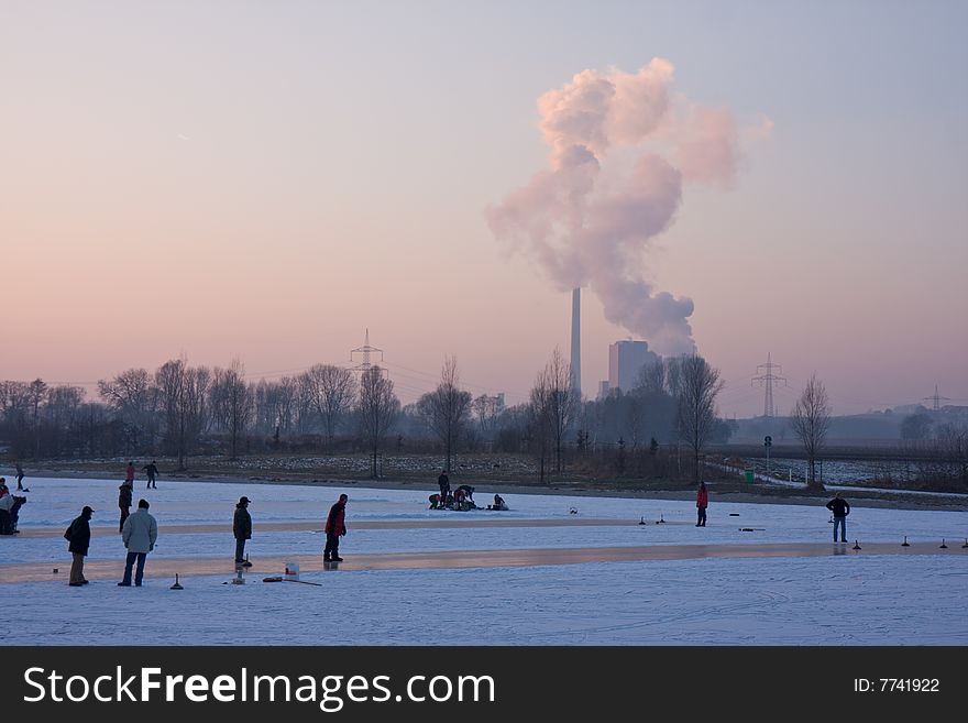 A frozen lake at sunset with a power station