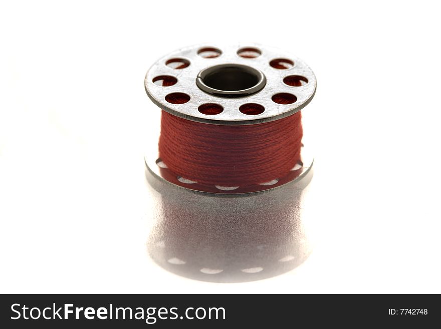 Round metallic spool of red thread