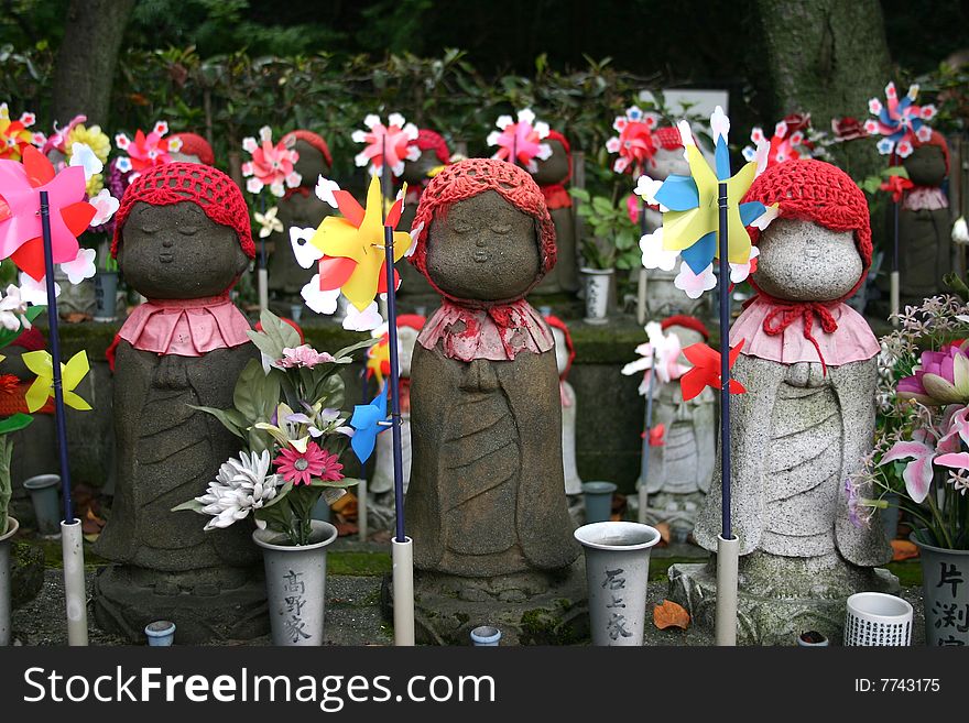 Japanese doll statues with red hats and windmills