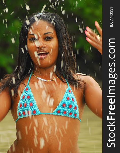 Island girl in bikini splashing water from ocean on seashore. Grenada, Wet Indies. Island girl in bikini splashing water from ocean on seashore. Grenada, Wet Indies