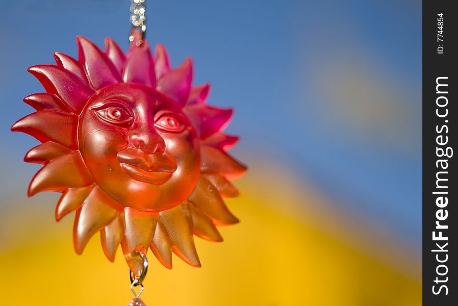 Smiling sun face craft object hanging with copy space in vibrant colorful sky area