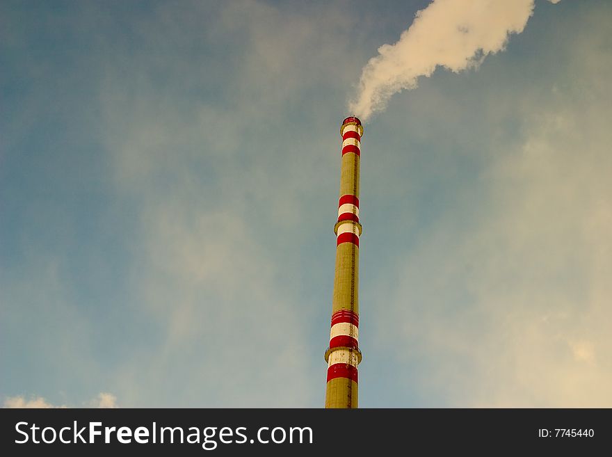 The chimney of a factory with white smoke. The chimney of a factory with white smoke
