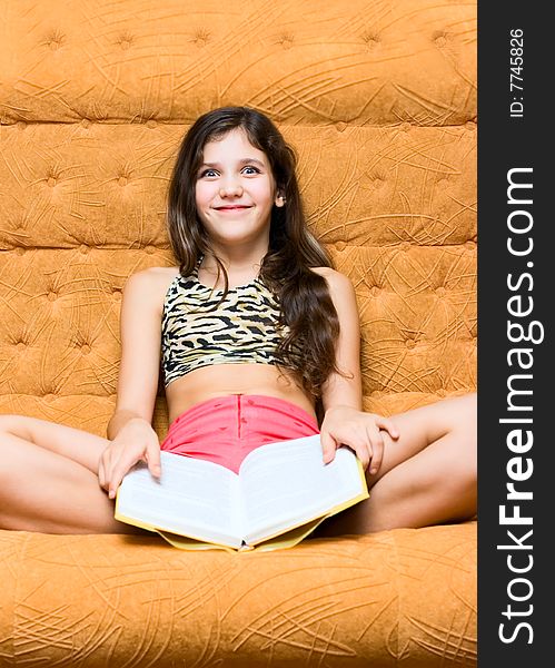 Teen girl reading book on sofa