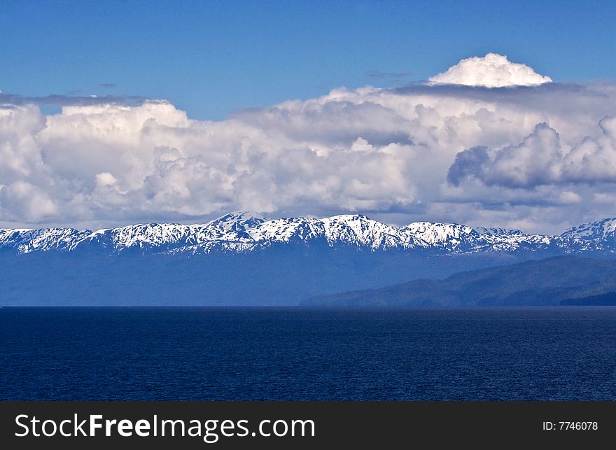 View from the Inside Passage of snow covered mountain against cloudy skies. View from the Inside Passage of snow covered mountain against cloudy skies.