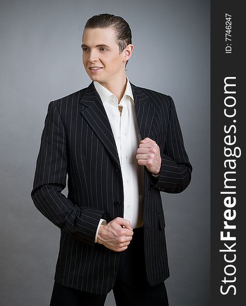 Young smiling businessman on grey background. Young smiling businessman on grey background