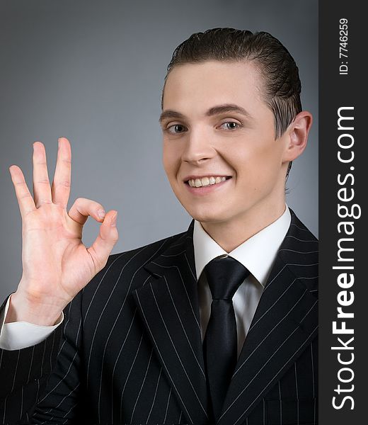 Young smiling businessman giving okay sign. Young smiling businessman giving okay sign