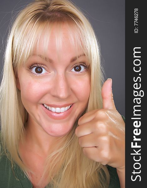 Beautiful Woman with a Thumbs Up Against a Grey Background.