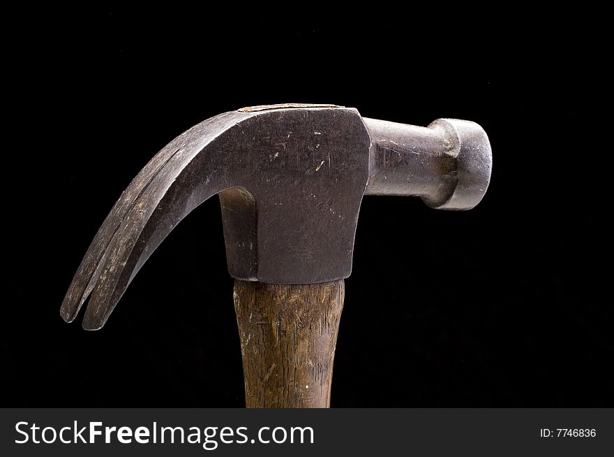 Old wood handled hammer against a black background