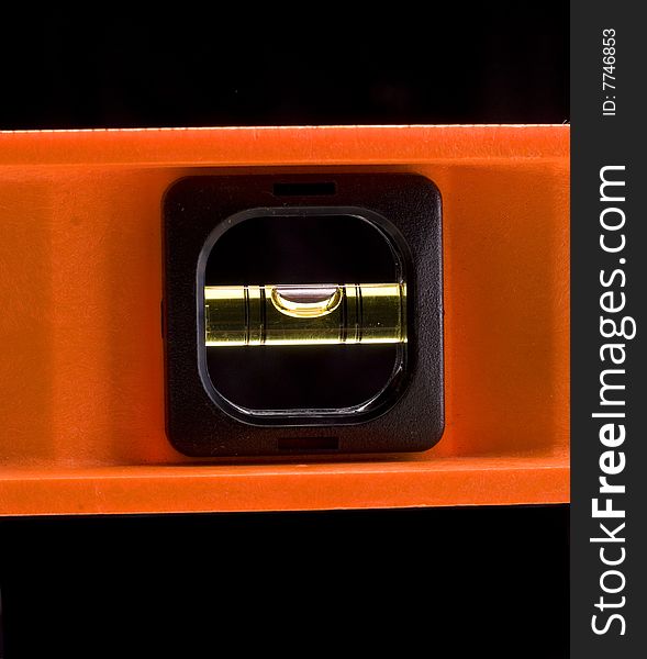 Orange spirit level against a black background