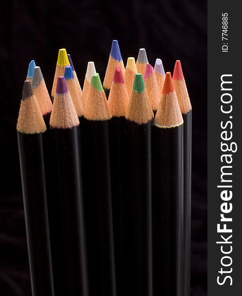 Colored pencils lined up on a black background