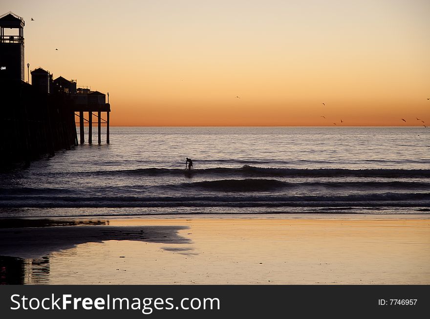 A lone surfer in silhouette tries his luck at catching a last-minute wave near a pier on Southern California's coast. A lone surfer in silhouette tries his luck at catching a last-minute wave near a pier on Southern California's coast.