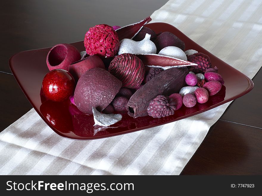 Red potpourri arrangement on glass plate and fabric table runner