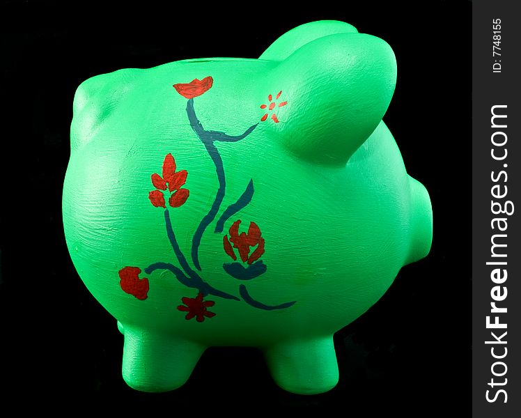 Painted piggy bank with floral design on a black vinyl background. Background burned for isolation. Painted piggy bank with floral design on a black vinyl background. Background burned for isolation.