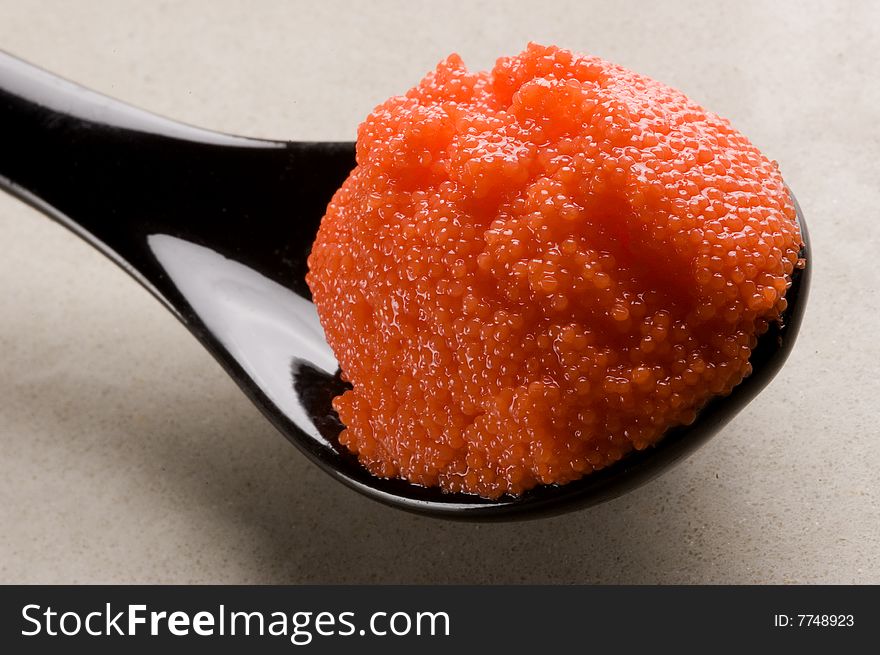 Red russian caviar in a black spoon