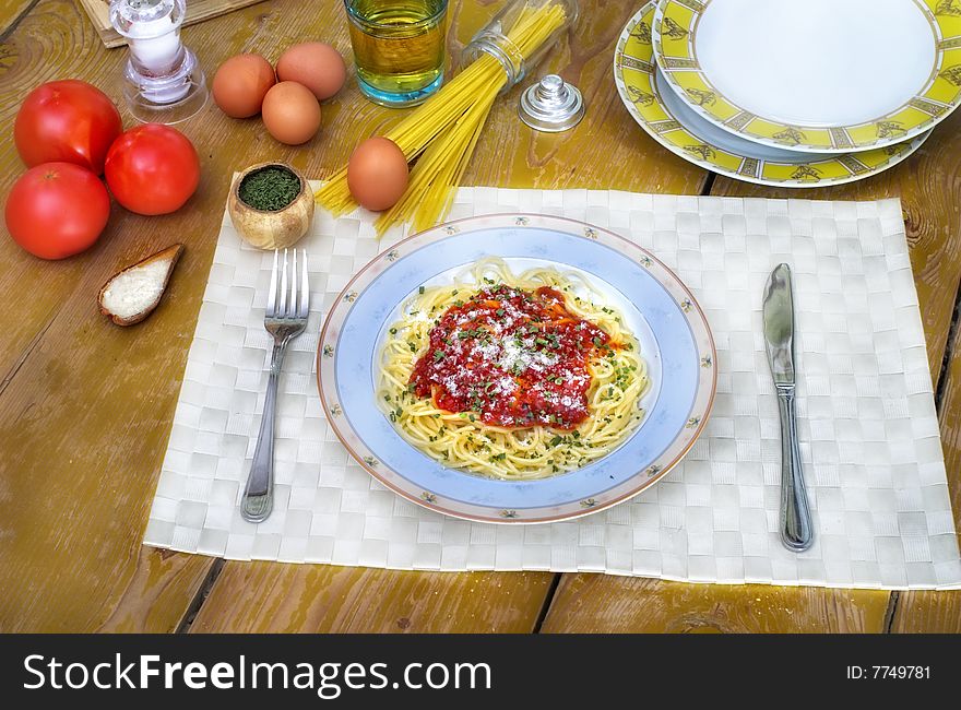 Spaghetti and tomato sauce on wooden desk