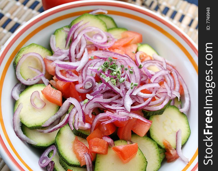 A bowl with zucchini, tomatoes and onions. A bowl with zucchini, tomatoes and onions