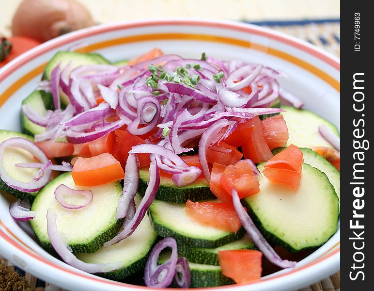 A bowl with zucchini, tomatoes and onions. A bowl with zucchini, tomatoes and onions