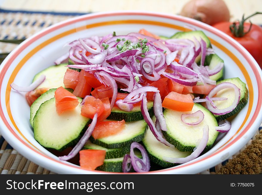 A bowl with zucchini, tomatoes and onions. A bowl with zucchini, tomatoes and onions