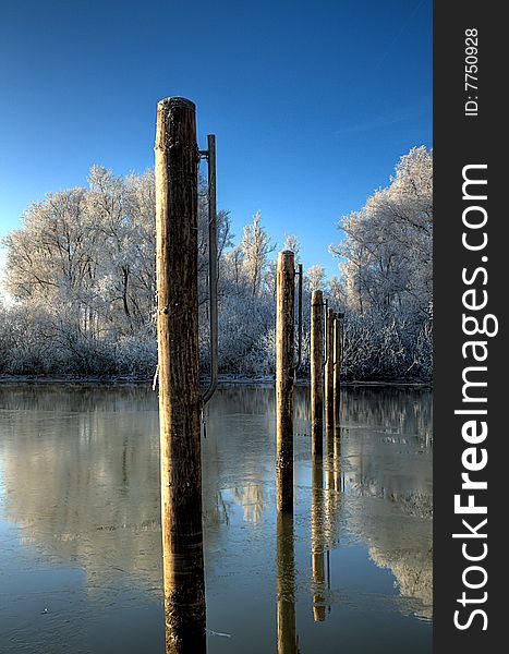 Winter scene with poles in the icy water