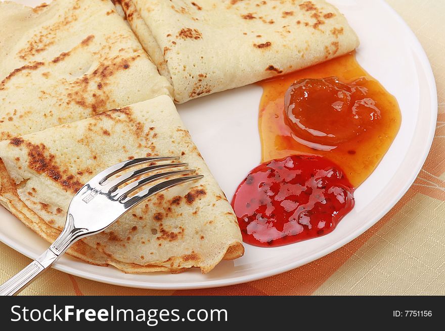 Three tasty pancakes on white plate with berry jam
