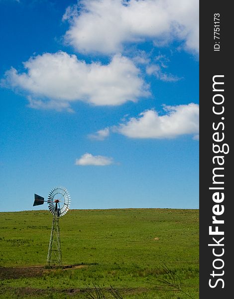 Beautiul windmill in green field against blue sky with clouds