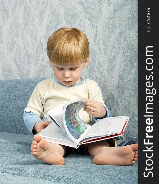 The little boy with the book sitting on a sofa. The little boy with the book sitting on a sofa