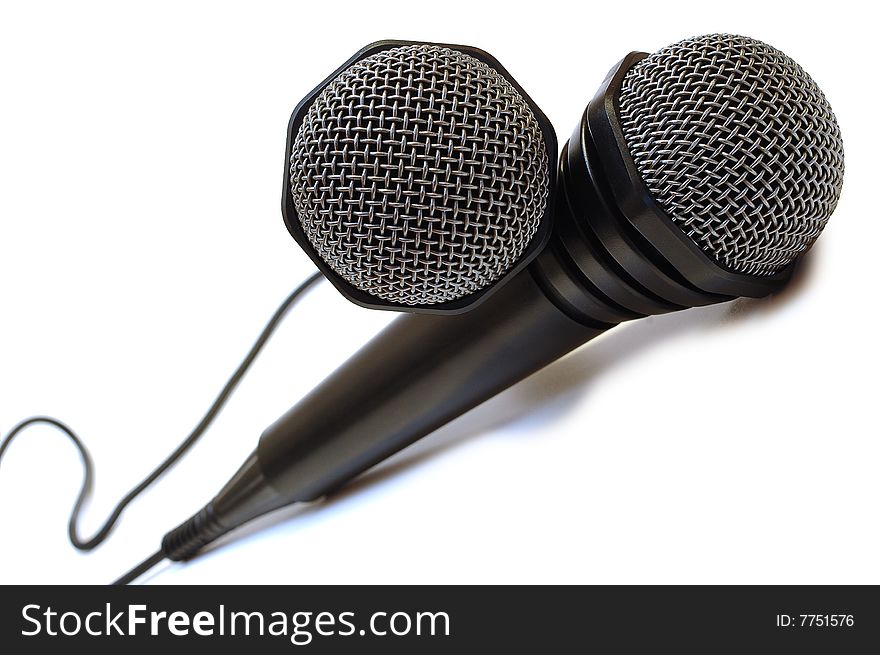 Two black wired karaoke microphones with gray metal grill on isolated background. Two black wired karaoke microphones with gray metal grill on isolated background.