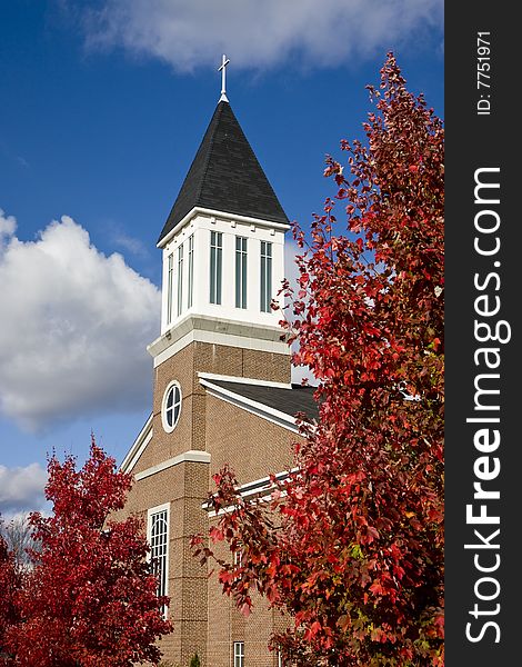 A modern brick church with autumn trees and partly cloudy sky. A modern brick church with autumn trees and partly cloudy sky