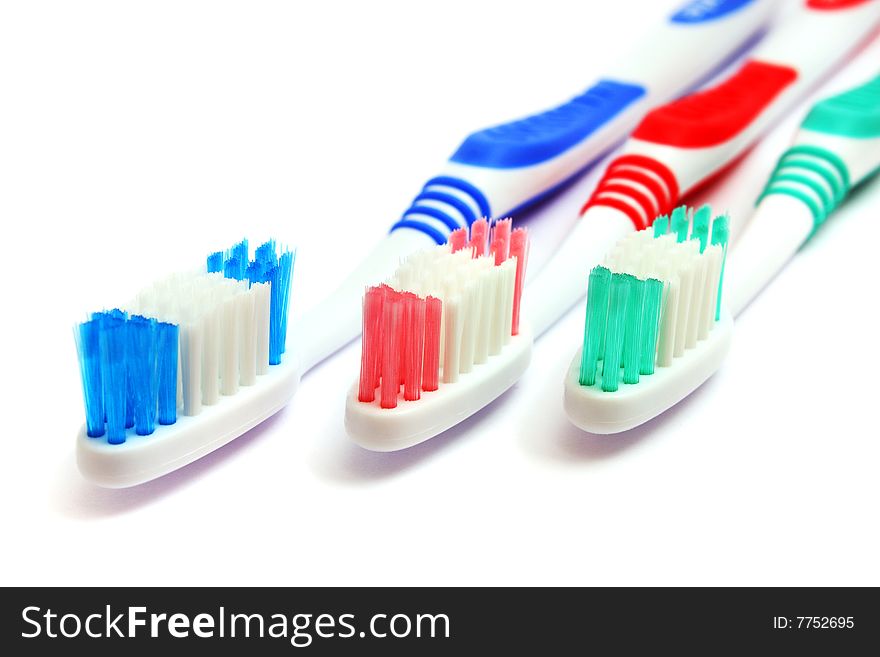 Close up of three different color tooth brush on white background.