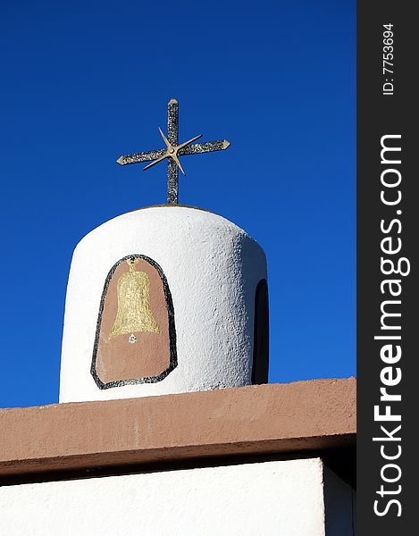 A cross made of wrought iron at the top of a chapel