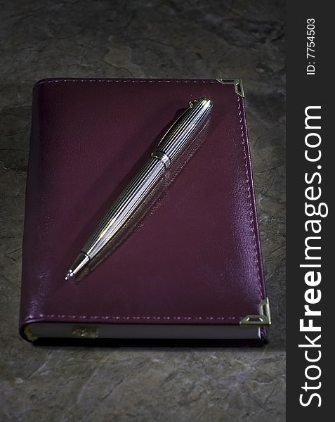 Small notebook with a golden pen on top of stone