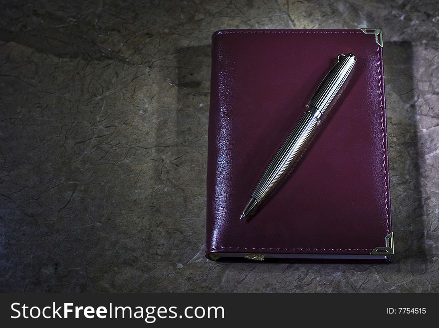 Small notebook with a golden pen on stone