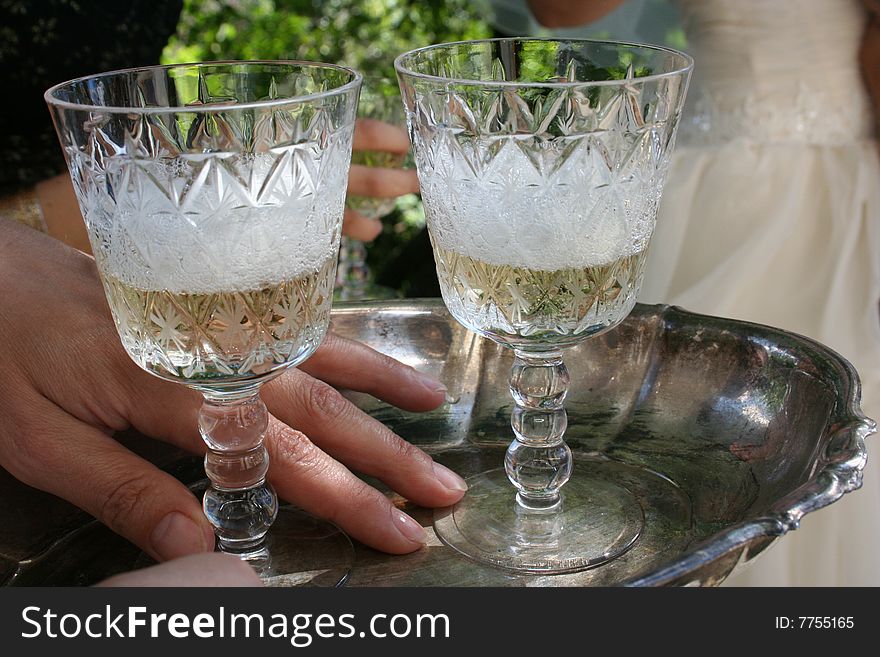 Two glasses of champagne are on a silver tray. Two glasses of champagne are on a silver tray.