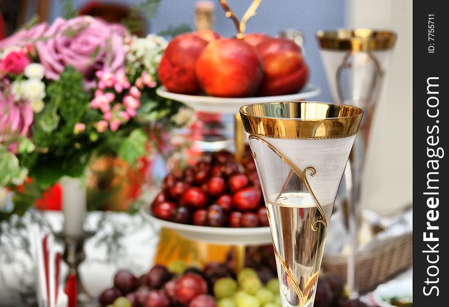 Glass with champagne against a bouquet and fruit. Glass with champagne against a bouquet and fruit