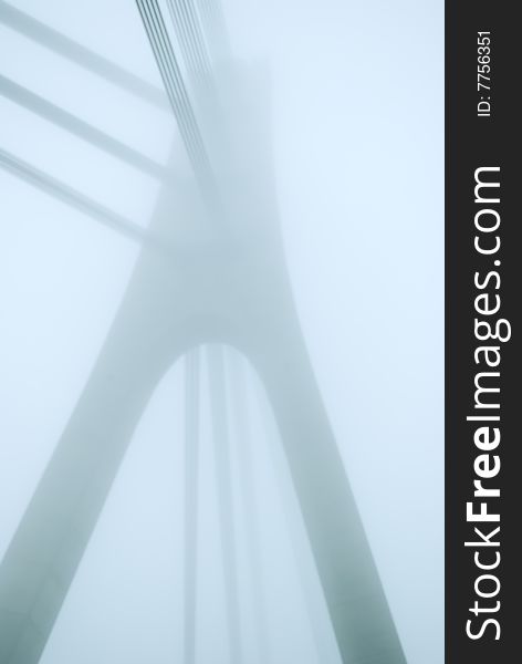 Industrial constructions are in fog, details of bridge are in a grey color