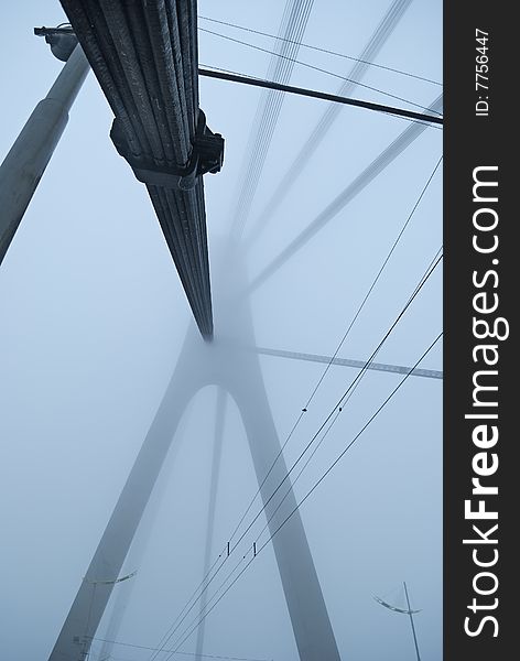 Industrial constructions are in fog, details of bridge are in a grey color