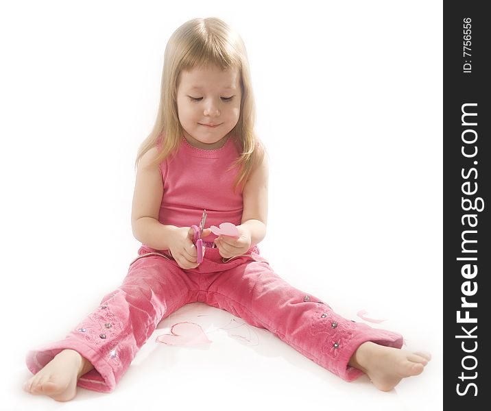 Pretty small girl in red is cutting paper heart shape