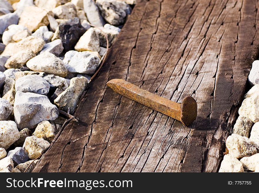 A railroad spike lying on a railroad tie with gravel on either side.