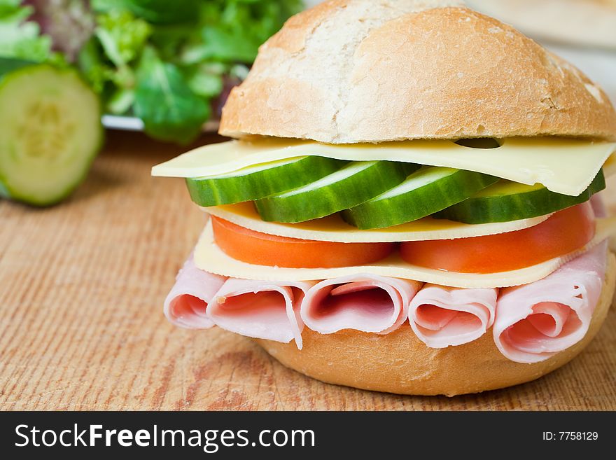 Delicious ham, cheese and salad sandwich on a wooden board