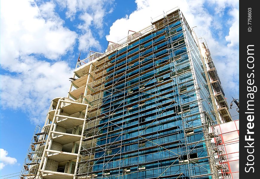 High building of glass and concrete on a blue sky background. 
under construction. High building of glass and concrete on a blue sky background. 
under construction