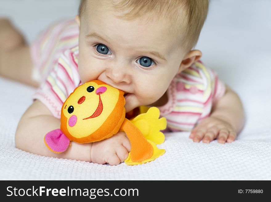 Little girl laying on a white bed playing with a toy monkey. Little girl laying on a white bed playing with a toy monkey